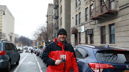 Sal Mena holding a photo while standing in his Bronx neighborhood