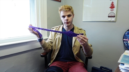 student holds purple bow tie