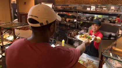 Mongolian Grill station cook Hsyeh Lin Chiu serves food to student Abuchi Oguonu (SCI '19) at the Livingston Dining Hall