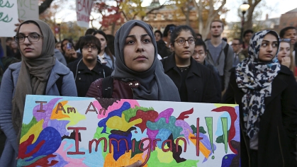group of students and one holds a sign saying I am an immigrant
