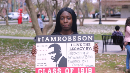 student holds sign that says I live the legacy by celebarting and acknowledging Black excellence on campus