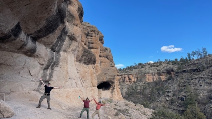 Participants in the GO Outdoors program pose in front of a cliff face