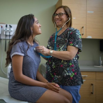 nurse uses stethoscope to listen to student's heart