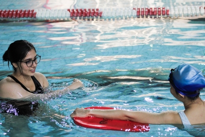 A swim instructor helps a participant at Swim School in Spring 2024